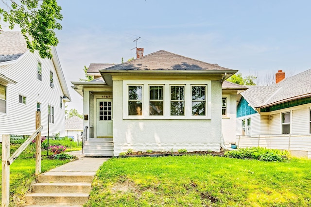 1167 Geranium Ave E, Saint Paul, MN 55106 - bungalow featuring stucco siding, a front lawn, a chimney, and roof with shingles