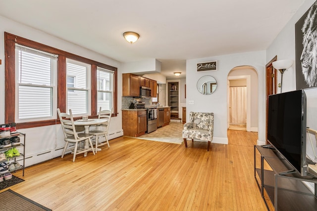 1167 Geranium Ave E, Saint Paul, MN 55106 - living room with light wood-style floors, arched walkways, a baseboard radiator, and baseboards