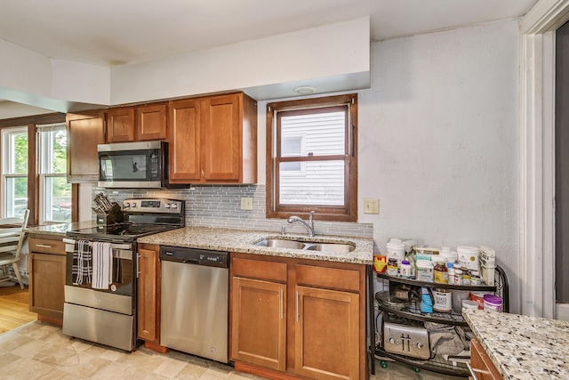 1167 Geranium Ave E, Saint Paul, MN 55106 - kitchen featuring appliances with stainless steel finishes, a sink, brown cabinetry, light stone countertops, and backsplash
