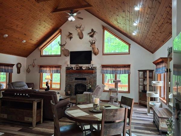 29805 Arbo Rd, Grand Rapids, MN 55744 - dining room featuring high vaulted ceiling, wooden ceiling, a ceiling fan, wood finished floors, and a stone fireplace