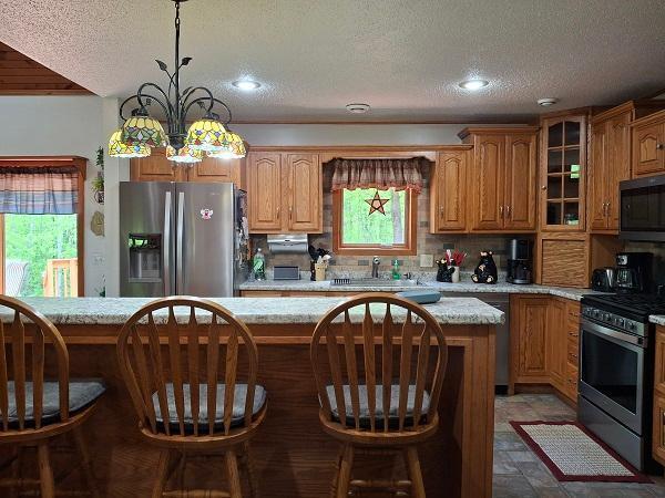 29805 Arbo Rd, Grand Rapids, MN 55744 - kitchen with appliances with stainless steel finishes, a sink, a kitchen bar, a textured ceiling, and glass insert cabinets