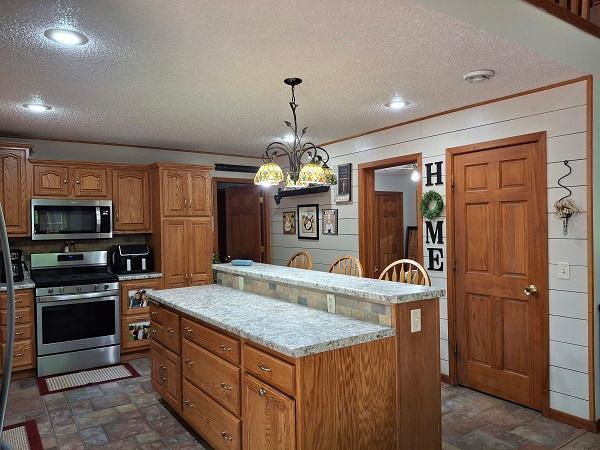 29805 Arbo Rd, Grand Rapids, MN 55744 - kitchen with stainless steel appliances, a textured ceiling, light countertops, a center island, and hanging light fixtures