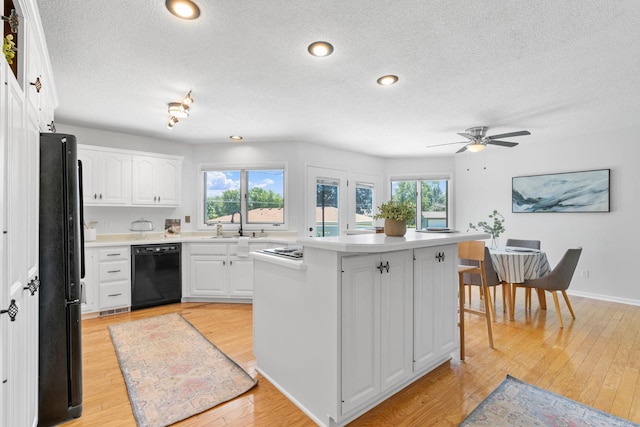 6540 Zealand Ave N, Brooklyn Park, MN 55428 - kitchen featuring black appliances, a textured ceiling, light wood-style floors, white cabinetry, and light countertops