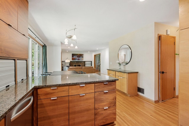 10933 Chowen Ave S, Bloomington, MN 55431 - kitchen with light wood finished floors, a fireplace, a peninsula, dark stone countertops, and open floor plan