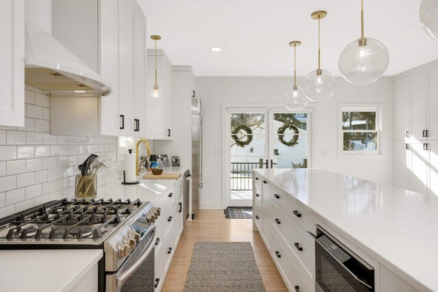 150 1st St, Excelsior, MN 55331 - kitchen featuring gas range, custom exhaust hood, white cabinets, decorative backsplash, and light wood finished floors