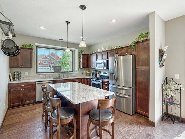 6024 158th St W, Apple Valley, MN 55124 - kitchen featuring appliances with stainless steel finishes, a sink, a kitchen island, a kitchen bar, and wood finished floors
