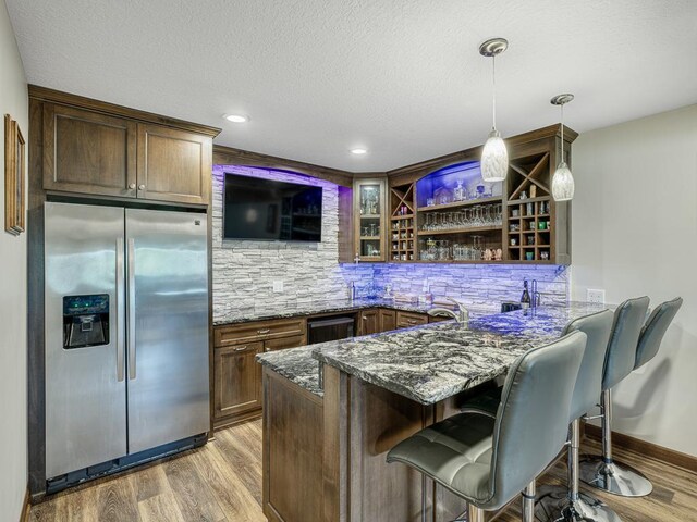 6024 158th St W, Apple Valley, MN 55124 - indoor wet bar with stainless steel fridge, light wood-style flooring, decorative light fixtures, a textured ceiling, and decorative backsplash