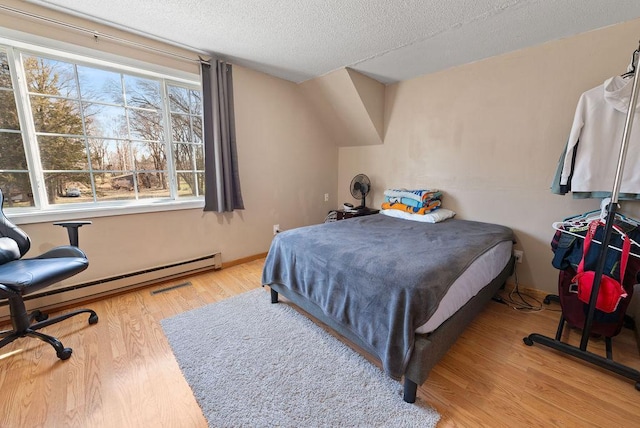 408 State St E, Grey Eagle, MN 56336 - bedroom with wood finished floors, a textured ceiling, and a baseboard heating unit