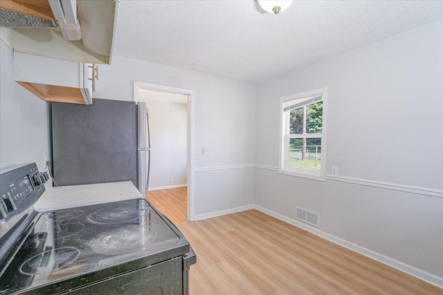 1637 37th Ave NE, Columbia Heights, MN 55421 - kitchen with electric stove, freestanding refrigerator, light wood-style floors, a textured ceiling, and baseboards