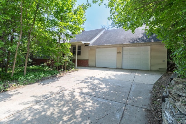 1700 Case Ave E, Saint Paul, MN 55106 - view of front of house with concrete driveway, a garage, brick siding, and roof with shingles
