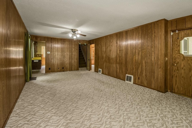 1700 Case Ave E, Saint Paul, MN 55106 - carpeted empty room with stairway, a ceiling fan, wooden walls, and a textured ceiling