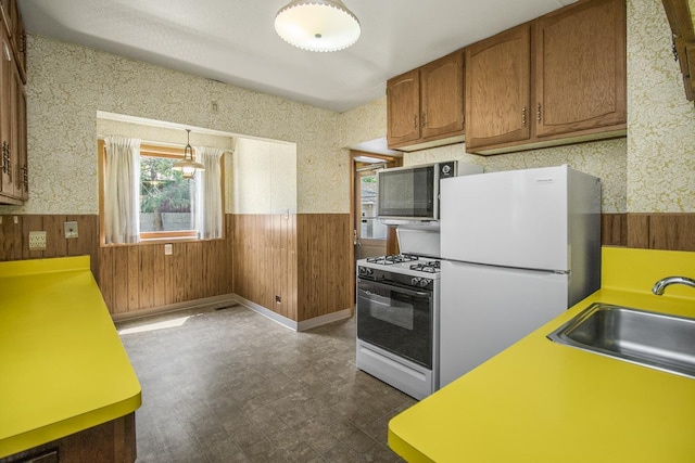 1700 Case Ave E, Saint Paul, MN 55106 - kitchen with white appliances, a wainscoted wall, wood walls, a sink, and wallpapered walls