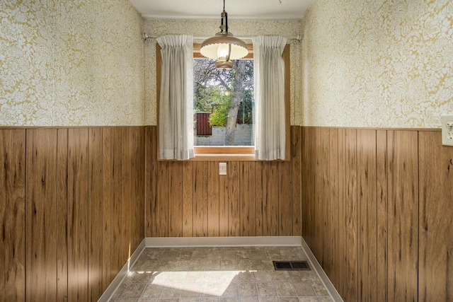 1700 Case Ave E, Saint Paul, MN 55106 - unfurnished dining area featuring a wainscoted wall, wallpapered walls, and wooden walls