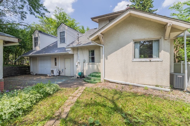 1700 Case Ave E, Saint Paul, MN 55106 - rear view of property featuring central AC unit, driveway, an attached garage, and stucco siding