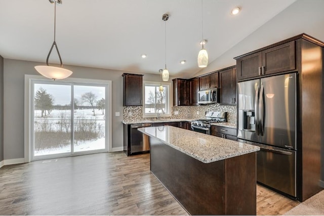 4781 261st St, Wyoming, MN 55092 - kitchen with stainless steel appliances, dark brown cabinets, decorative backsplash, lofted ceiling, and light stone counters