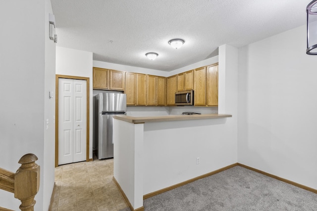 15481 Frost Path Unit 1803, Apple Valley, MN 55124 - kitchen with stainless steel appliances, a peninsula, brown cabinets, a textured ceiling, and light countertops