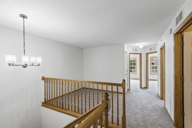 15481 Frost Path Unit 1803, Apple Valley, MN 55124 - hallway featuring an upstairs landing, carpet flooring, a chandelier, and a textured ceiling