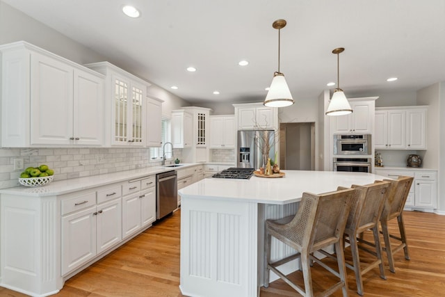 600 Sibley Ct, Mendota Heights, MN 55118 - kitchen with stainless steel appliances, a sink, a kitchen island, decorative backsplash, and white cabinetry