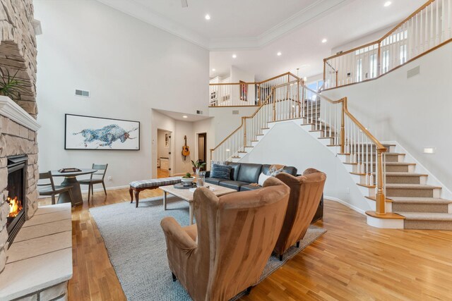 600 Sibley Ct, Mendota Heights, MN 55118 - living room featuring stairs, a towering ceiling, a stone fireplace, wood finished floors, and ornamental molding