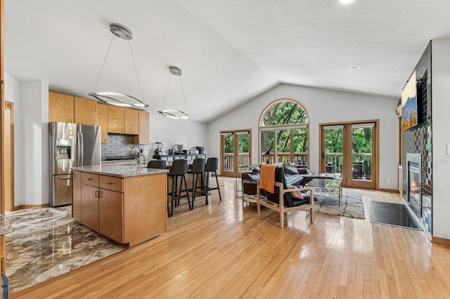 2665 Oriole Ave N, West Lakeland Twp, MN 55082 - kitchen with stainless steel fridge, open floor plan, light wood-type flooring, a center island with sink, and lofted ceiling