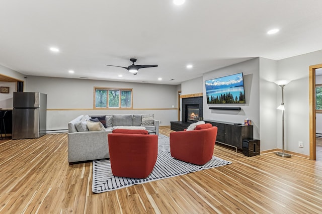 2665 Oriole Ave N, West Lakeland Twp, MN 55082 - living area with wood finished floors, a baseboard heating unit, a fireplace, a ceiling fan, and recessed lighting