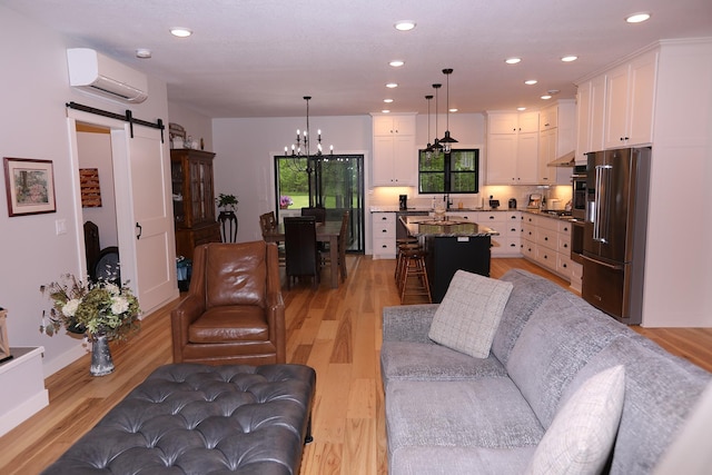 5004 W Rd, Silver Twp, MN 55767 - living area with a barn door, a wall unit AC, a chandelier, light wood-style flooring, and recessed lighting