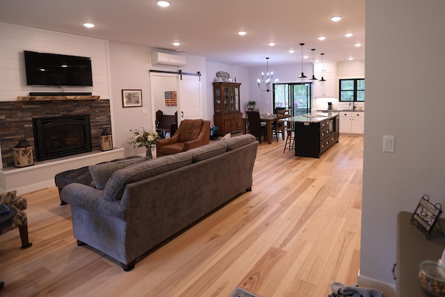 5004 W Rd, Silver Twp, MN 55767 - living area with an AC wall unit, a barn door, light wood-style flooring, recessed lighting, and a stone fireplace