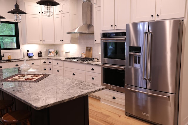 5004 W Rd, Silver Twp, MN 55767 - kitchen with appliances with stainless steel finishes, wall chimney range hood, light wood-style flooring, white cabinetry, and a breakfast bar