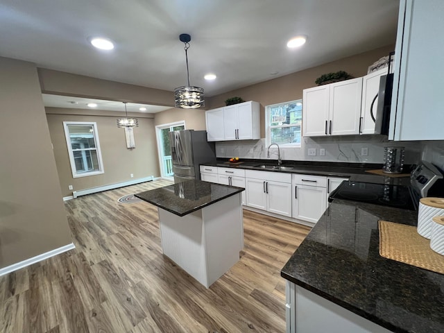 975 4th St E, Saint Paul, MN 55106 - kitchen with stainless steel appliances, a baseboard radiator, a sink, light wood-style flooring, and backsplash