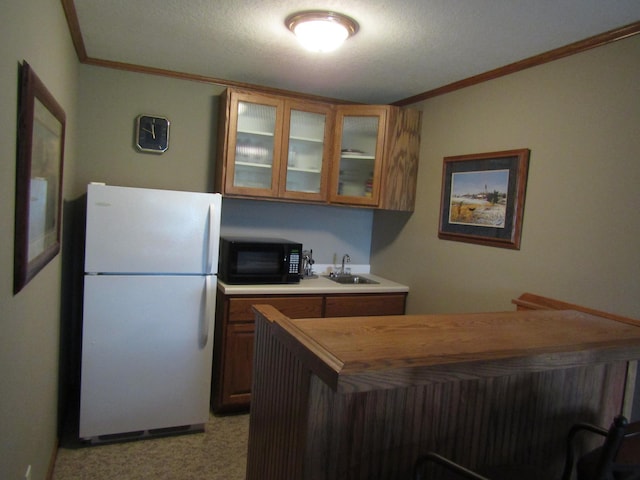 180 Bordson St, Appleton, MN 56208 - kitchen with freestanding refrigerator, black microwave, a sink, brown cabinets, and ornamental molding