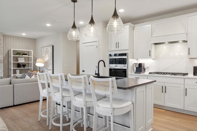 14625 105th Pl N, Maple Grove, MN 55369 - kitchen featuring appliances with stainless steel finishes, open floor plan, light wood finished floors, a center island with sink, and white cabinets