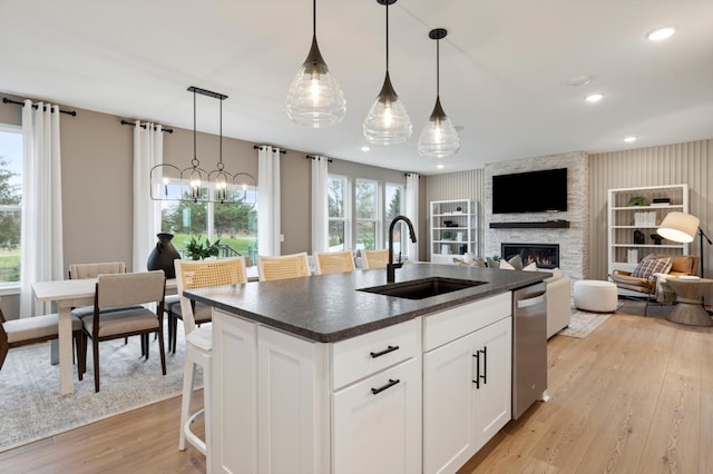 14625 105th Pl N, Maple Grove, MN 55369 - kitchen featuring a sink, dark countertops, stainless steel dishwasher, light wood-style flooring, and a fireplace