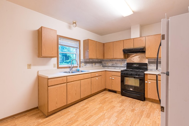 475 Minnehaha Ave E, Saint Paul, MN 55130 - kitchen with black gas range oven, freestanding refrigerator, a sink, under cabinet range hood, and light wood finished floors