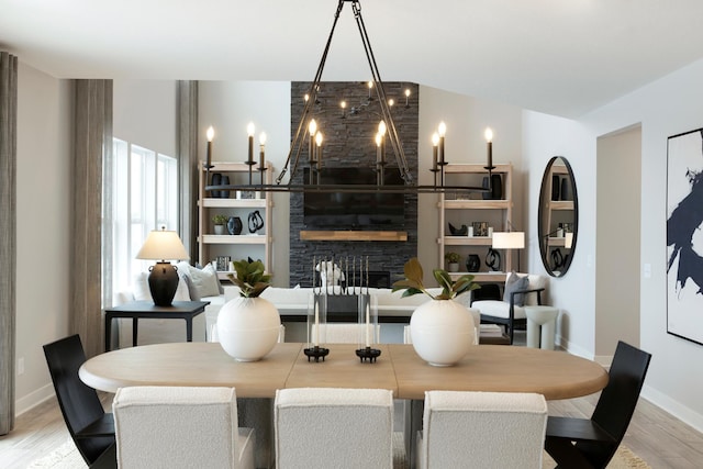 14705 105th Pl N, Maple Grove, MN 55369 - dining space with light wood-type flooring, baseboards, a chandelier, and a stone fireplace
