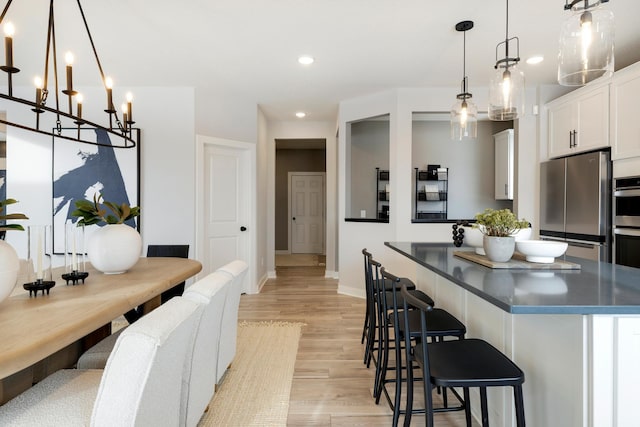 14705 105th Pl N, Maple Grove, MN 55369 - kitchen featuring stainless steel appliances, white cabinets, a kitchen island, a breakfast bar area, and light wood finished floors