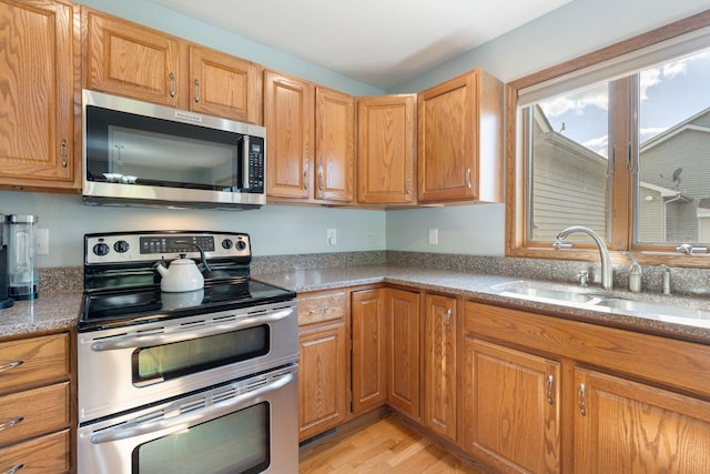 2800 9th Ave SW, Austin, MN 55912 - kitchen featuring stainless steel appliances, a sink, light wood-style flooring, and light stone countertops