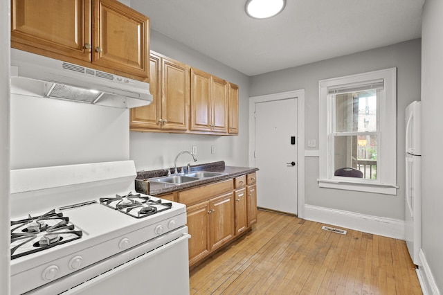 3400 Elliot Ave S, Minneapolis, MN 55407 - kitchen with white appliances, under cabinet range hood, a sink, dark countertops, and baseboards