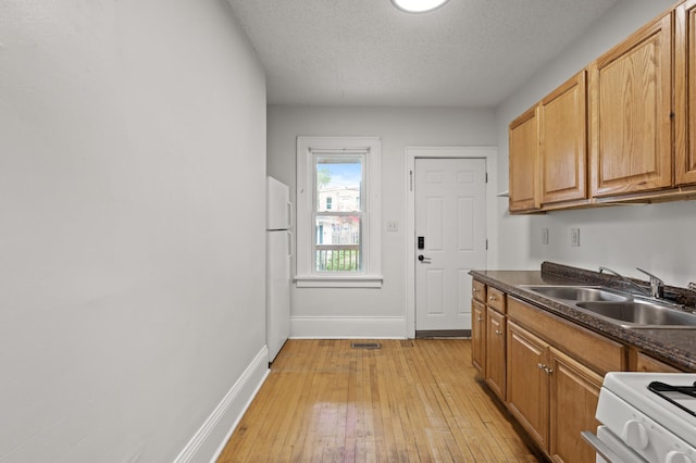 3400 Elliot Ave S, Minneapolis, MN 55407 - kitchen with a sink, white appliances, dark countertops, light wood finished floors, and baseboards