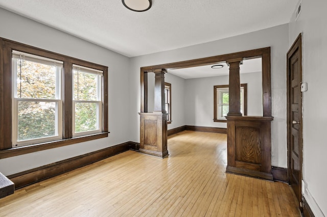 3400 Elliot Ave S, Minneapolis, MN 55407 - empty room with ornate columns, light wood-style flooring, plenty of natural light, and baseboards