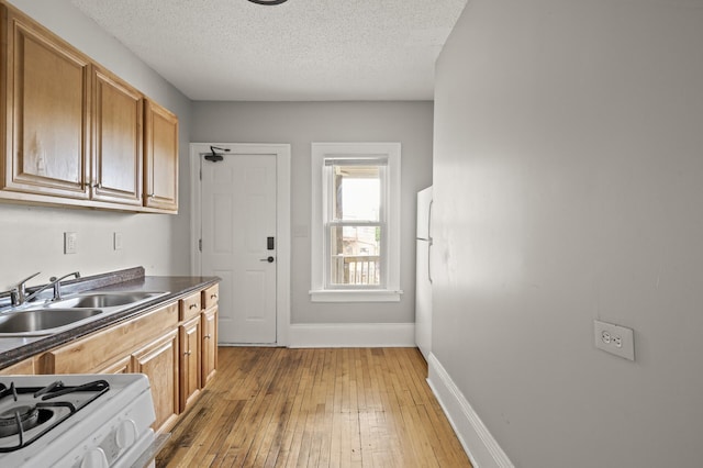 3400 Elliot Ave S, Minneapolis, MN 55407 - kitchen featuring a sink, dark countertops, baseboards, light wood-style floors, and a textured ceiling