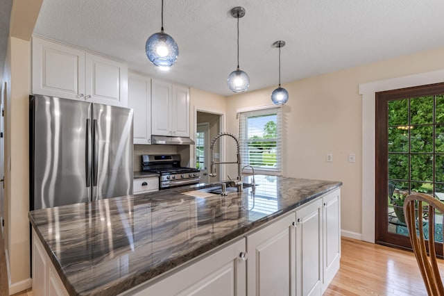 72 7th St, Cochrane, WI 54622 - kitchen featuring appliances with stainless steel finishes, light wood-style flooring, white cabinetry, dark stone countertops, and a kitchen island with sink