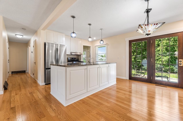 72 7th St, Cochrane, WI 54622 - kitchen featuring appliances with stainless steel finishes, light wood finished floors, white cabinetry, dark countertops, and pendant lighting