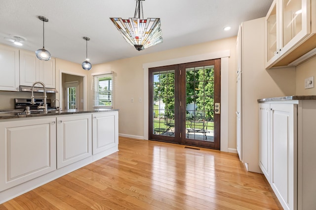 72 7th St, Cochrane, WI 54622 - kitchen with light wood-style flooring, white cabinetry, hanging light fixtures, glass insert cabinets, and recessed lighting