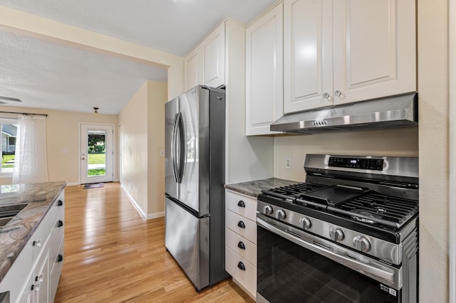 72 7th St, Cochrane, WI 54622 - kitchen with stainless steel appliances, under cabinet range hood, dark stone counters, light wood-type flooring, and white cabinets