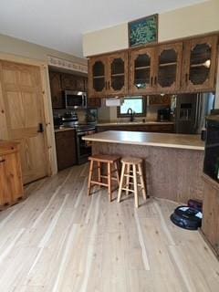 19146 Eaglewood Rd, Lynden Twp, MN 55320 - kitchen featuring black / electric stove, stainless steel microwave, light wood-style floors, glass insert cabinets, and a kitchen breakfast bar