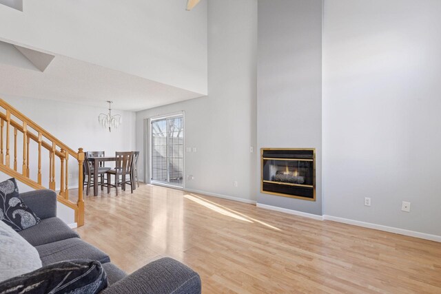 5995 Wedgewood Ln N Unit 84, Plymouth, MN 55446 - living area with a chandelier, wood finished floors, stairs, a glass covered fireplace, and baseboards