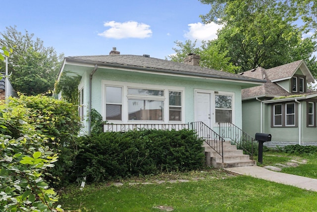 1104 21st Ave SE, Minneapolis, MN 55414 - view of front of property with stucco siding, a chimney, roof with shingles, and a front lawn
