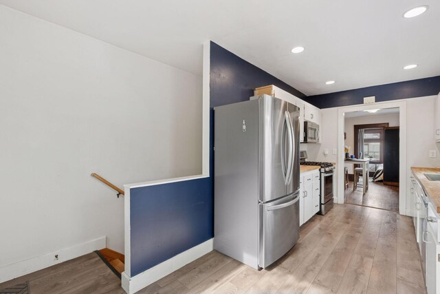 1104 21st Ave SE, Minneapolis, MN 55414 - kitchen with appliances with stainless steel finishes, white cabinets, light countertops, light wood-style flooring, and recessed lighting