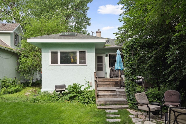 1104 21st Ave SE, Minneapolis, MN 55414 - rear view of house featuring stucco siding, a chimney, a yard, and entry steps