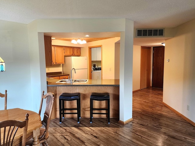 520 5th St SW Unit 318, Willmar, MN 56201 - kitchen with freestanding refrigerator, a sink, a chandelier, dark wood-type flooring, and a textured ceiling